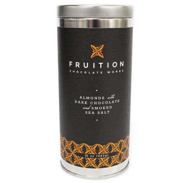 tall narrow metal tin with a black label with orange pattern along the bottom. The label reads "fruition chocolate works: almonds with dark chocolate and smoked sea salt"