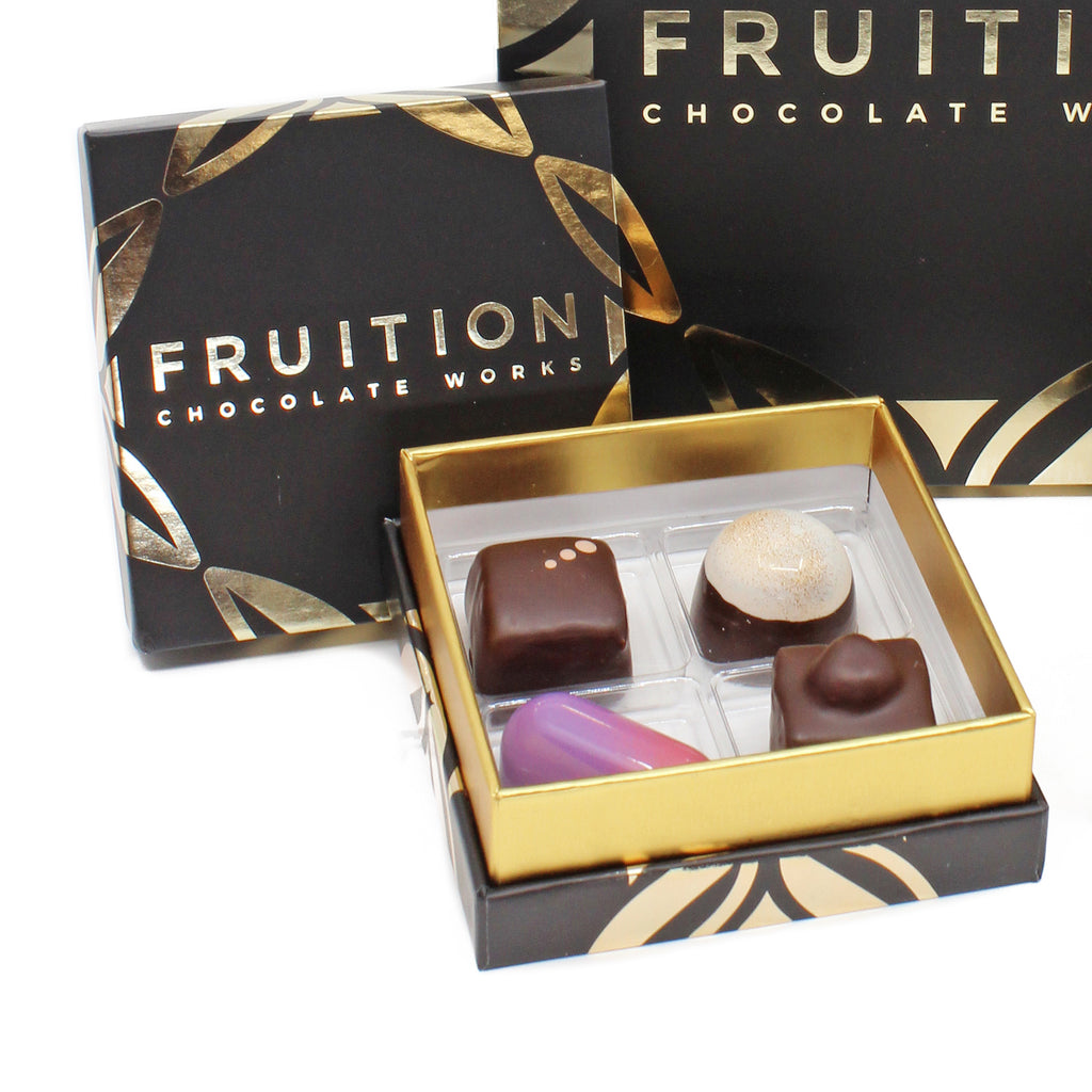 Black confection box containing 4 chocolate confections of various shapes and colors - Fruition Chocolate