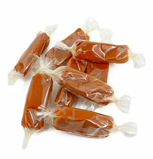 Caramel candies wrapped in clear plastic on a white background