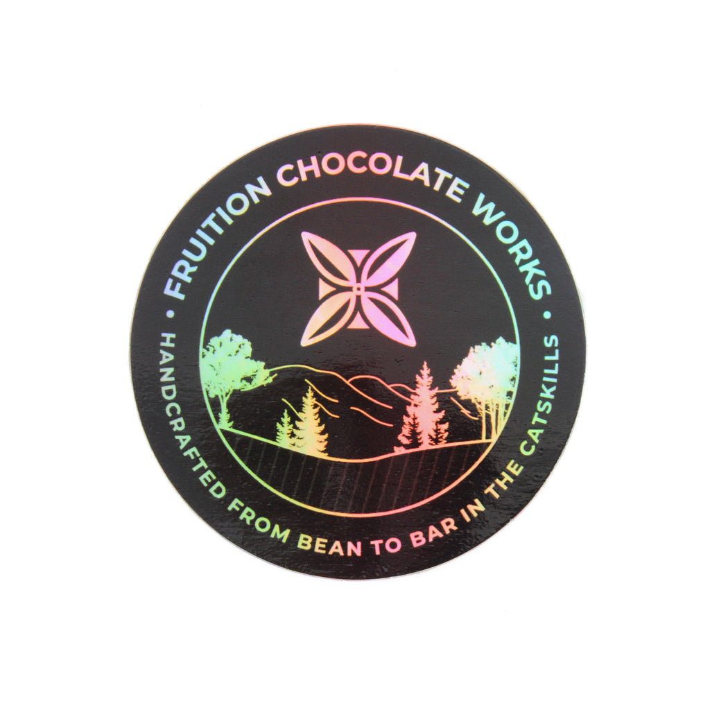 Round sticker with a black background, and the text and image are holographic. Text around the outside says "fruition chocolate works, handcrafted from bean to bar in the catskills", and the center is a drawing of mountains and trees