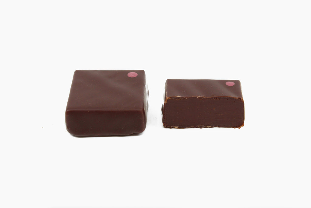 Two chocolate squares with a purple dot on the upper right corner. Smoked maple whiskey flavor