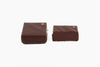 Two chocolate squares with a purple dot on the upper right corner. Smoked maple whiskey flavor