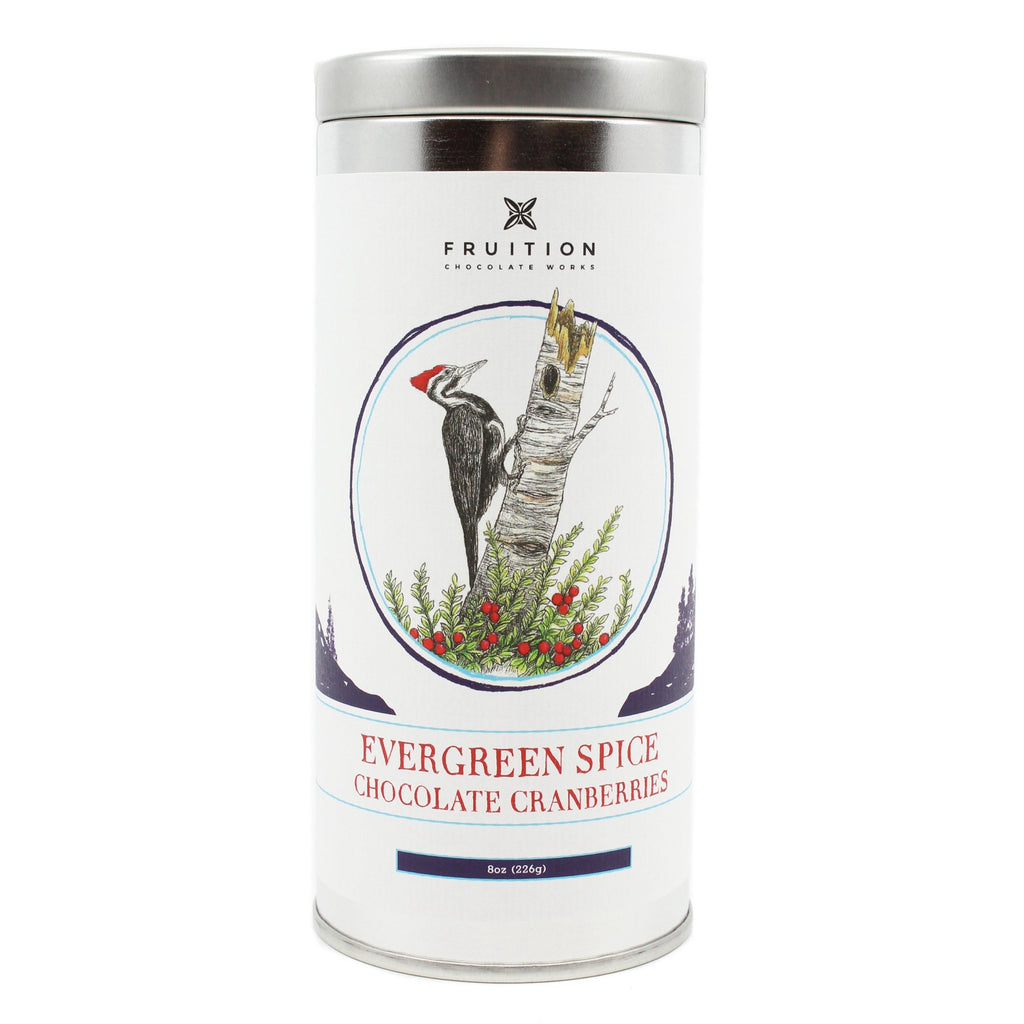 Metal tin with a white label featuring a woodpecker on a tree. Label reads "evergreen spice chocolate cranberries"