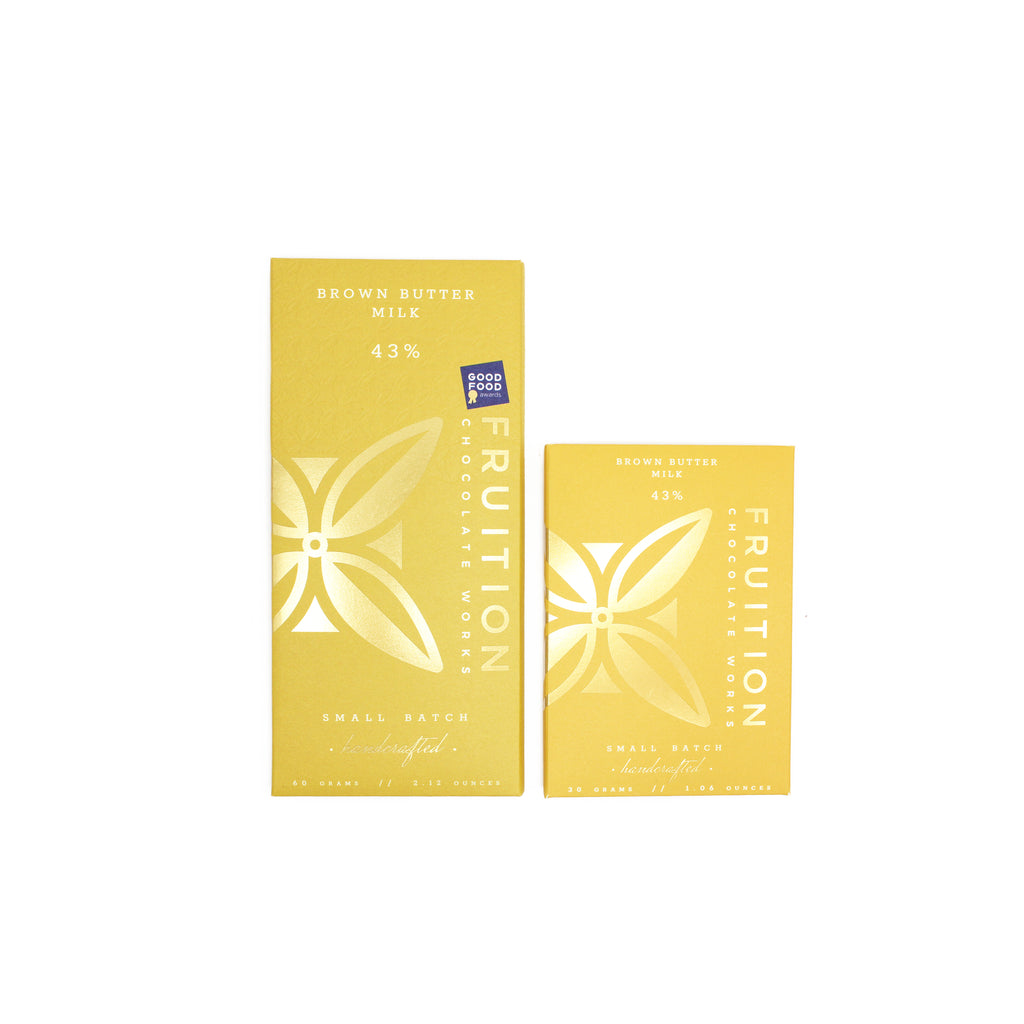 two yellow chocolate bars wrapper with gold foil logo on the front, one full size bar and one half size bar. The wrappers reads "brown butter milk 43%, fruition chocolate works"