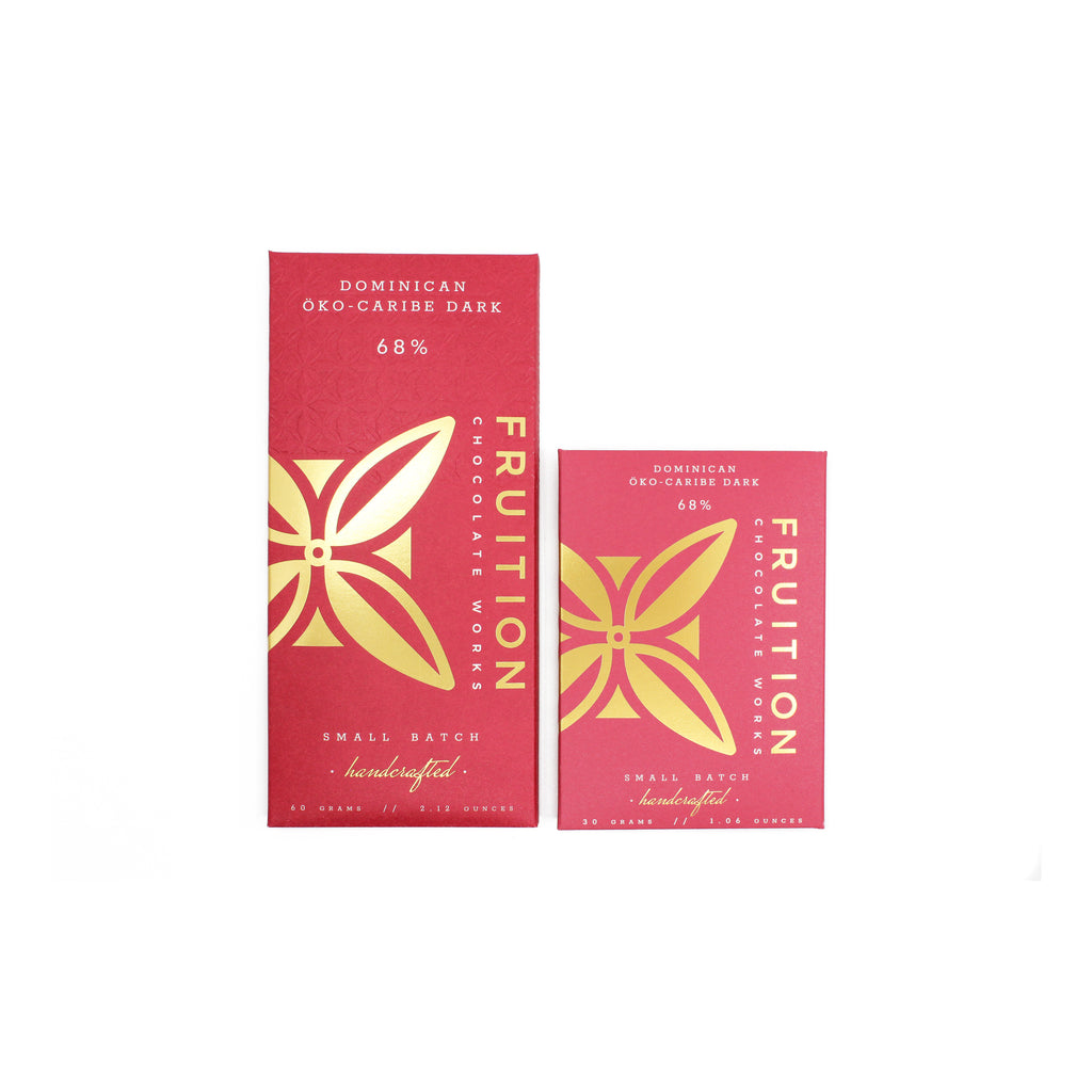 two red chocolate bar wrappers with gold foil logo on the front, one full size and one half size bar.. The wrappers read "dominican oko-caribe dark 68%, fruition chocolate works"